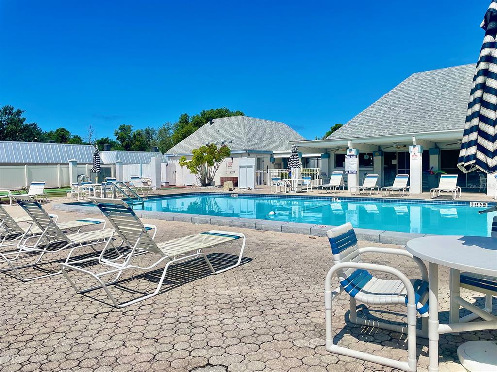4211 Sheldon Place, Unit 4211 New Port Richey, FL 34652 - Photo 53 of 58 a patio with tables and chairs pool and a fire pit with wooden fence