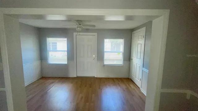 an empty room with wooden floor and windows