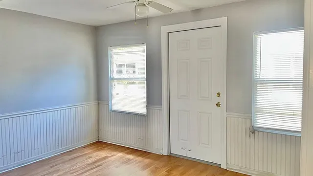 a view of an empty room with wooden floor and a window