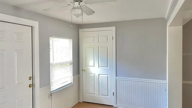 a view of empty room with wooden floor and fan