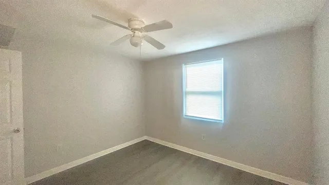 an empty room with a window and a fan