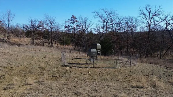 a view of a dry field with trees in background