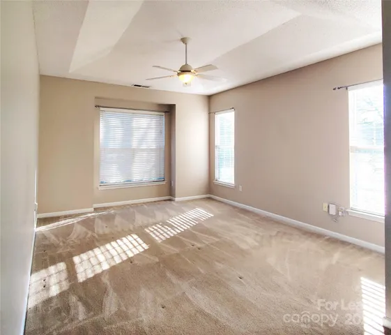 an empty room with windows and fan