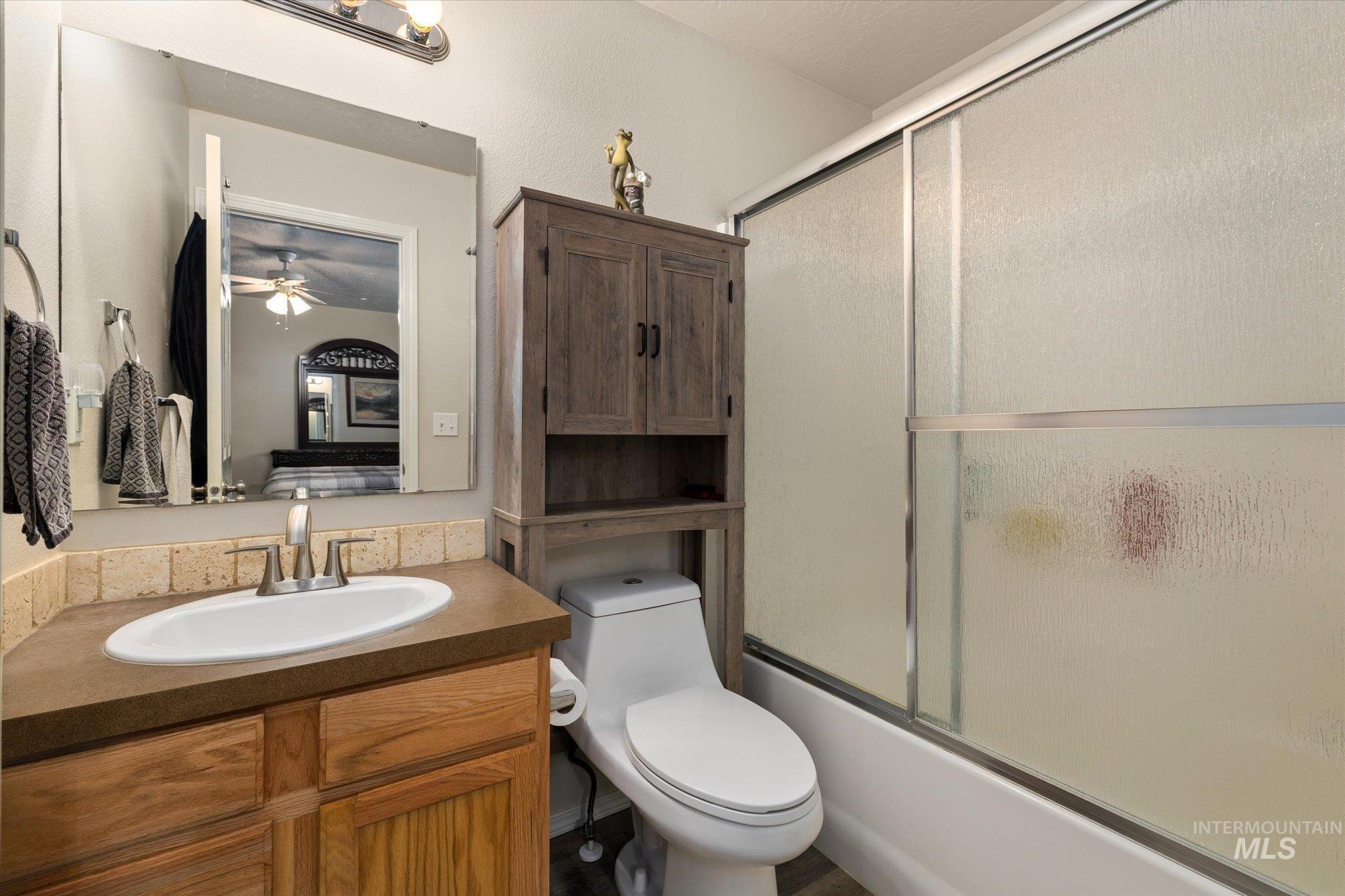5401 Barkley Way Caldwell, ID 83607 - Photo 14 of 35 Bathroom featuring a single vanity with a solid surface countertop, white oval sink, chrome faucet, and wood cabinetry