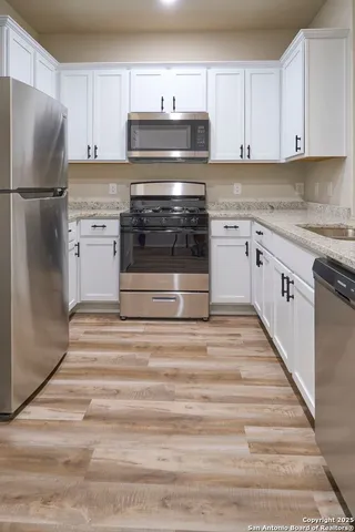 a kitchen with granite countertop white cabinets and stainless steel appliances