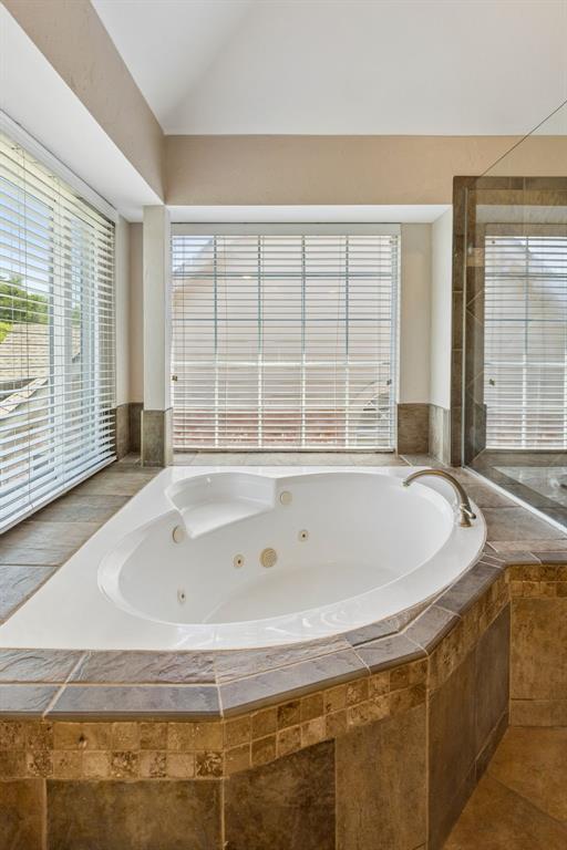2925 Sunset Ridge McKinney, TX 75072 - Photo 27 of 33 Relaxing jetted soaking tub surrounded by elegant tilework and oversized windows, creating a peaceful spa-like setting filled with natural light and tranquil outdoor views.