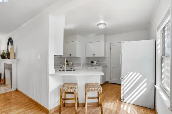 a kitchen with stainless steel appliances granite countertop a refrigerator a sink a stove and white cabinets with wooden floor