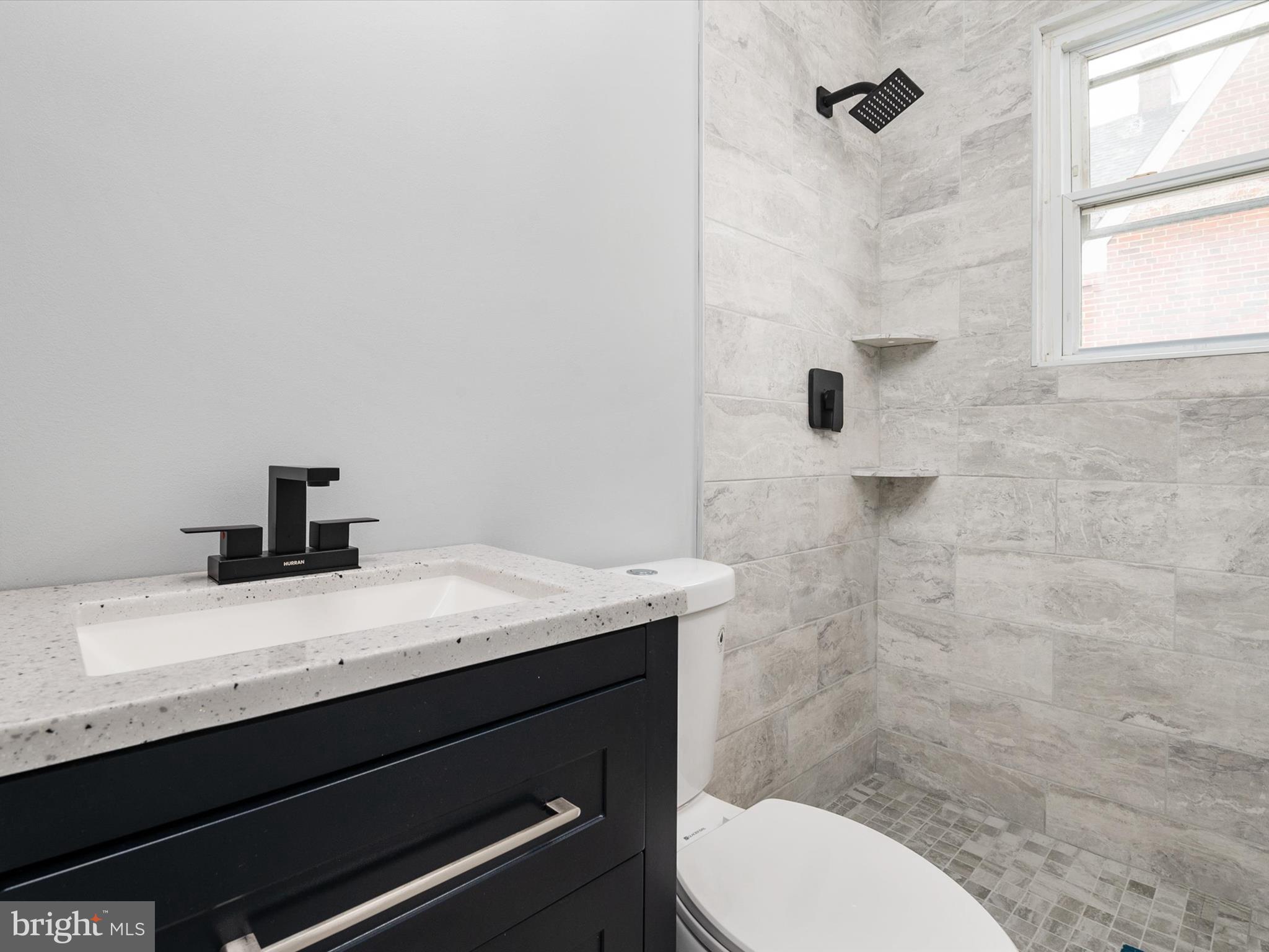 5002 Silver Hill Road Suitland, MD 20746 - Photo 16 of 39 a bathroom with a granite countertop sink toilet a mirror and shower