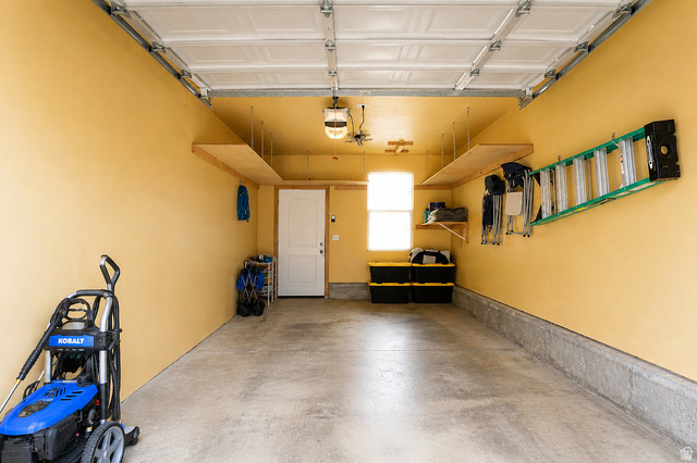 896 Cres Drive South Mapleton, UT 84664 - Photo 32 of 32 Spacious garage with concrete flooring, overhead garage door, built-in shelving, a side access door, and a transom window providing natural light