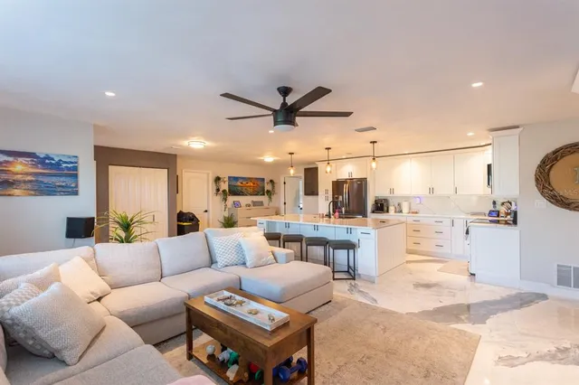 a living room with furniture a clock and a ceiling fan