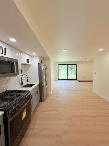 a large kitchen with stainless steel appliances granite countertop a stove and a refrigerator