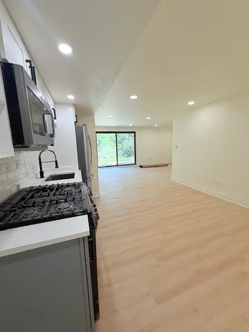 a large kitchen with stainless steel appliances a large counter top a stove and a sink