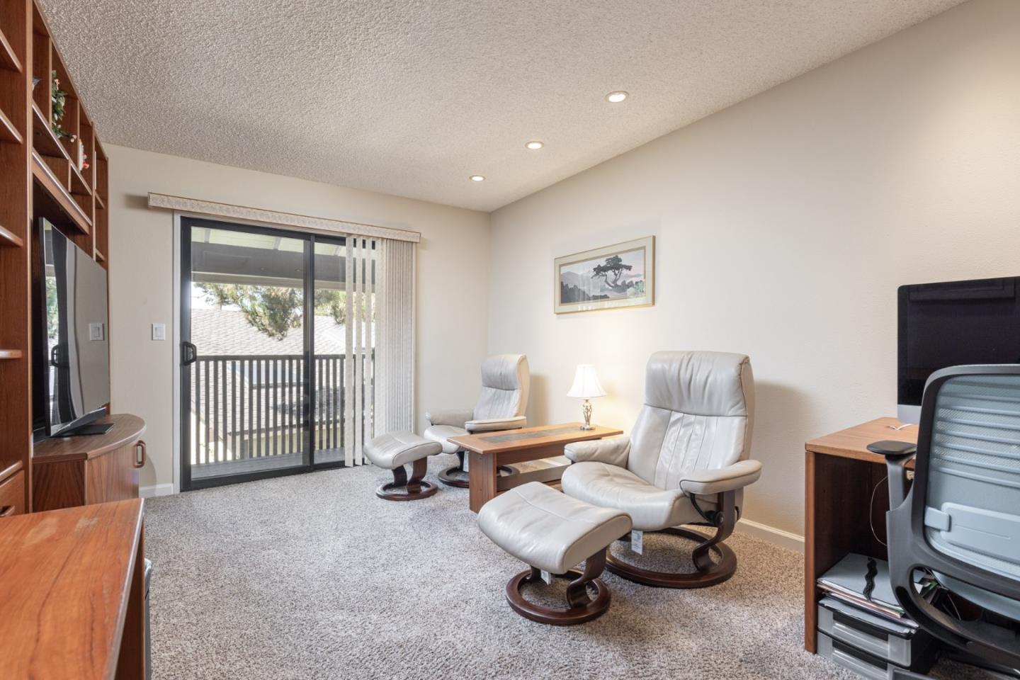 1360 Josselyn Canyon Road, Unit 40 Monterey, CA 93940 - Photo 15 of 18 a living room with furniture a flat screen tv and a window