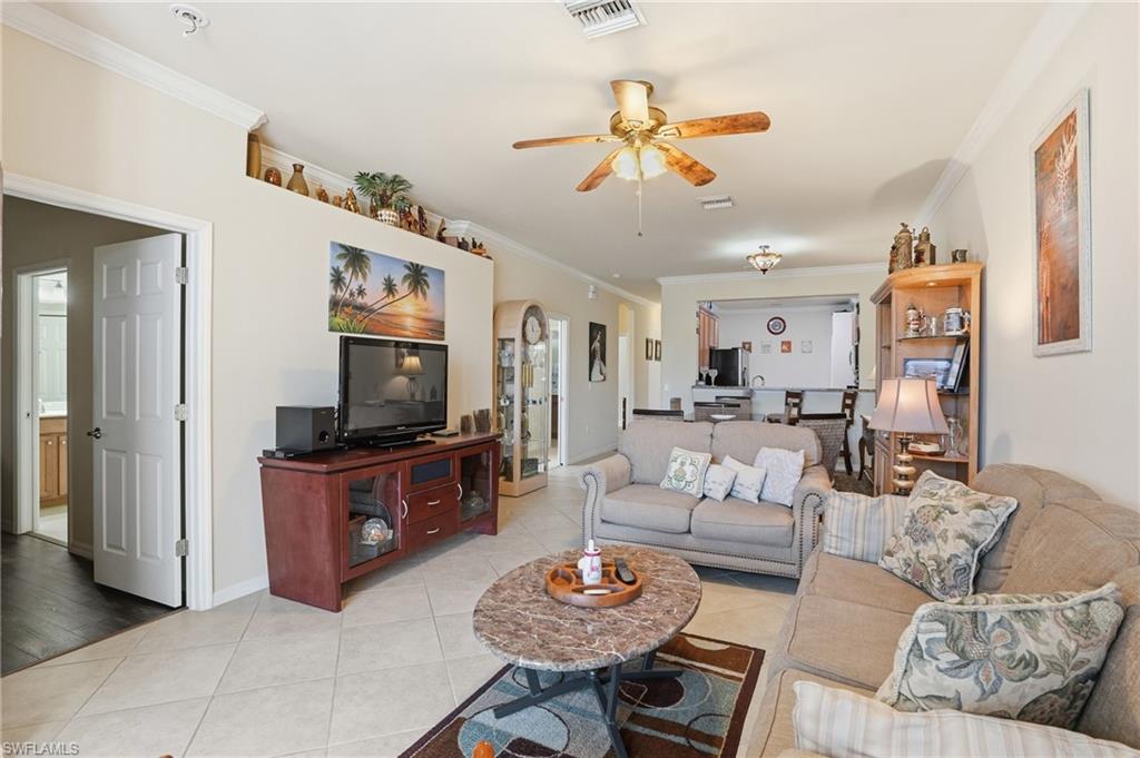 14536 Grapevine Drive Naples, FL 34114 - Photo 11 of 39 Living room featuring ornamental molding, a ceiling fan, light tile patterned flooring, and arched walkways