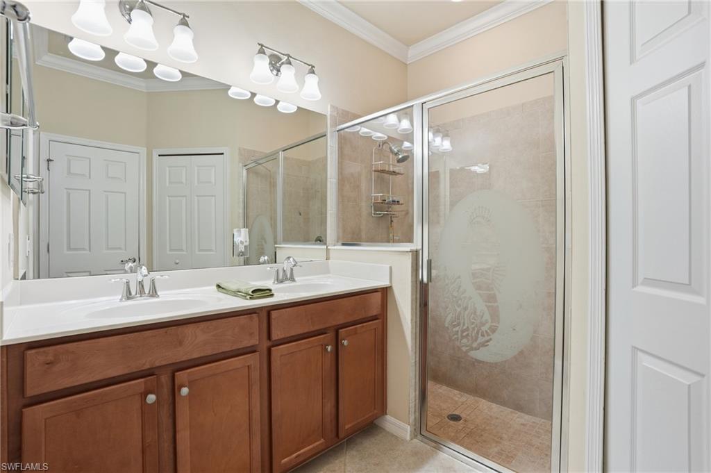 14536 Grapevine Drive Naples, FL 34114 - Photo 24 of 39 Bathroom featuring crown molding, double vanity, and a shower stall