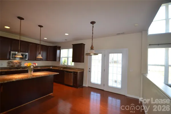 a kitchen with stainless steel appliances granite countertop a sink a stove and a wooden floors