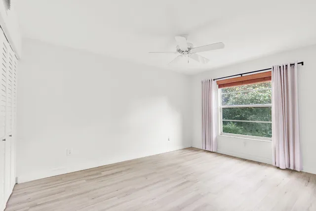an empty room with wooden floor fan and windows