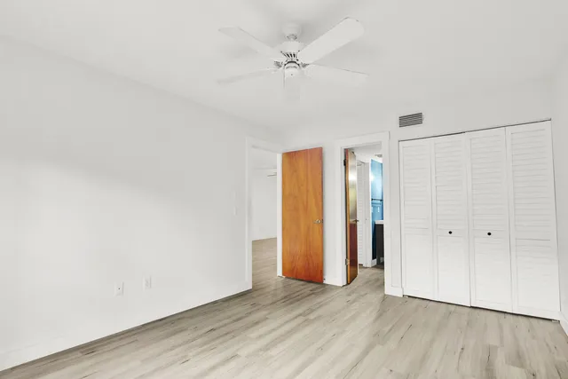an empty room with wooden floor and a ceiling fan