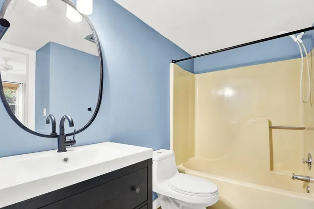 a bathroom with a sink a toilet a mirror and shower