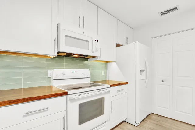 a kitchen with white cabinets and white appliances