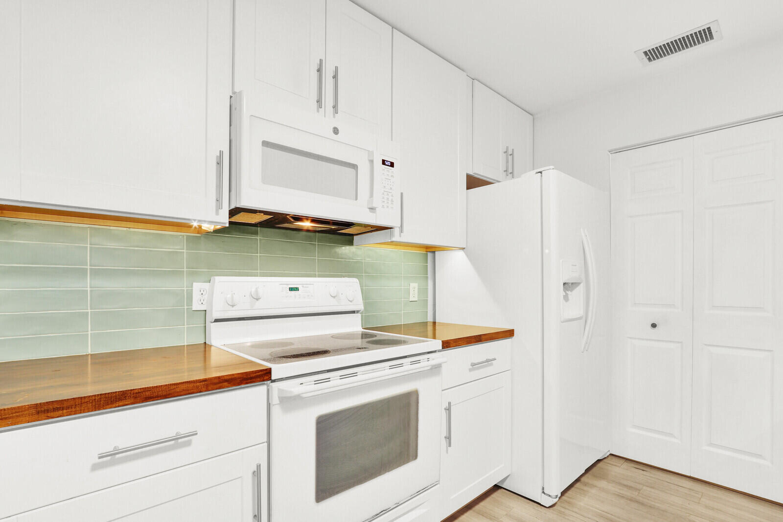 8356 Southeast Croft Circle, Unit O3 Hobe Sound, FL 33455 - Photo 6 of 20 a kitchen with white cabinets and white appliances