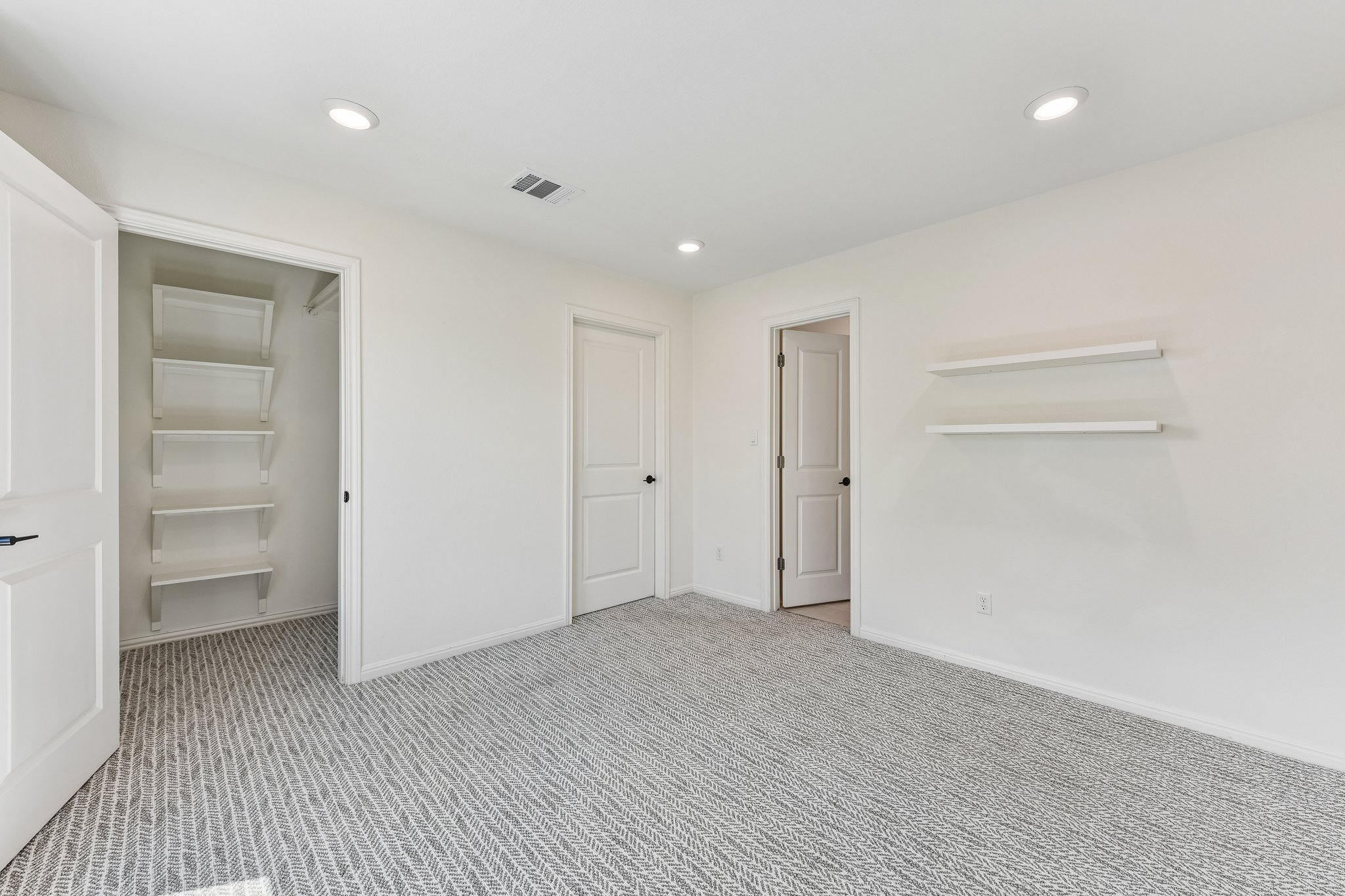 19113 Freeman Circle Austin, TX 78738 - Photo 20 of 37 A well-lit bedroom featuring modern recessed lighting and soft patterned carpeting.