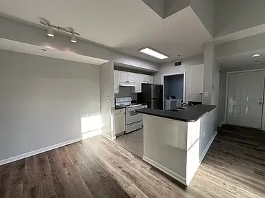 a large kitchen with stainless steel appliances a large counter top a stove a sink and a refrigerator