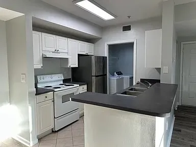 a kitchen with granite countertop a refrigerator stove and sink