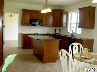 245 East Dell Road, Unit LOT10 Bath, PA 18014 - Photo 3 of 15 a kitchen with stainless steel appliances granite countertop a table chairs in it and wooden floors