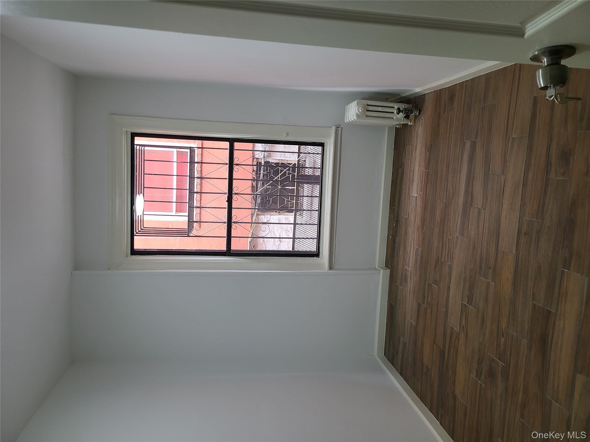 1309 Seneca Avenue Bronx, NY 10474 - Photo 13 of 20 a view of an empty room with wooden floor and a window