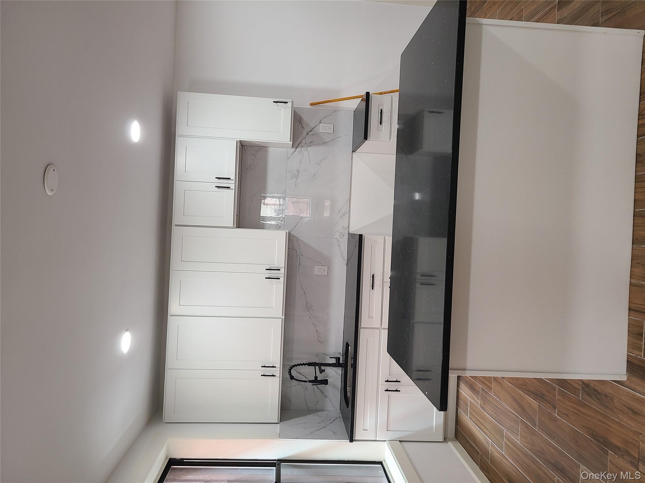 1309 Seneca Avenue Bronx, NY 10474 - Photo 14 of 20 a kitchen with kitchen island granite countertop a sink and white cabinets