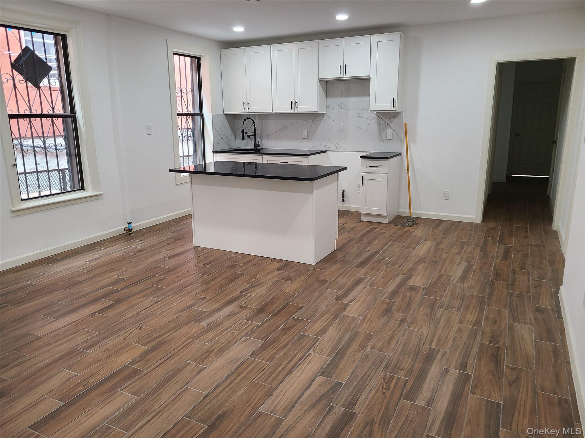 1309 Seneca Avenue Bronx, NY 10474 - Photo 17 of 20 a kitchen with stainless steel appliances granite countertop a white cabinets and wooden floor