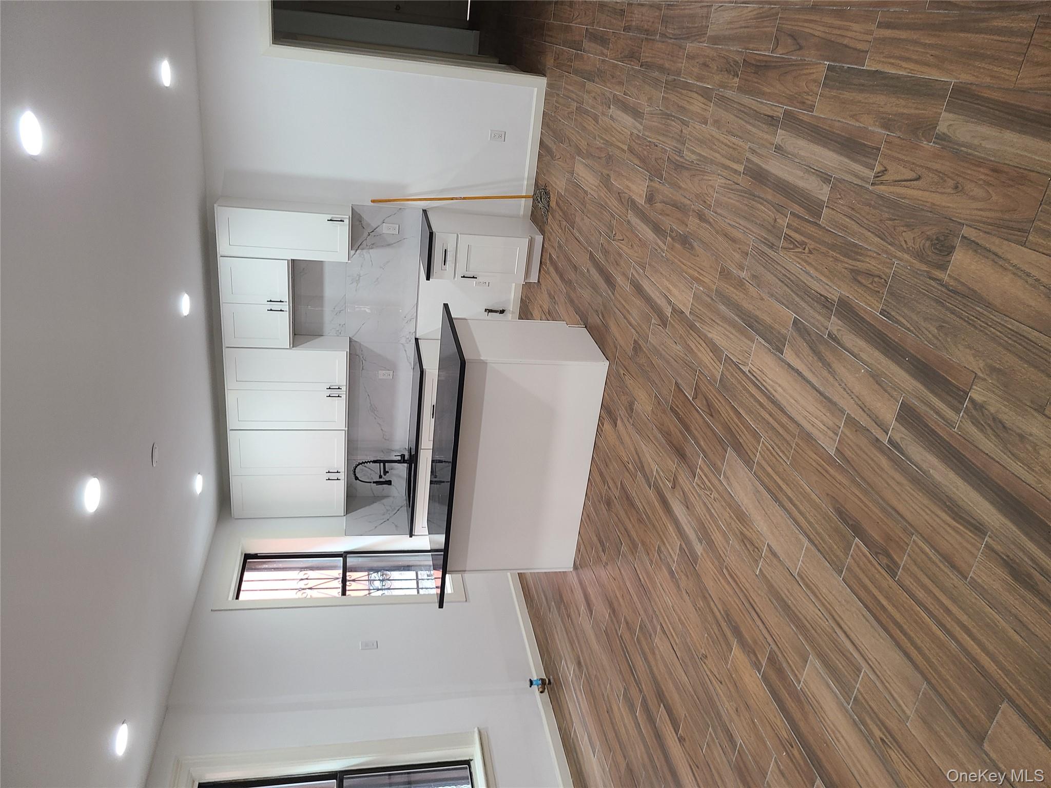 1309 Seneca Avenue Bronx, NY 10474 - Photo 3 of 20 an open kitchen with kitchen island a sink wooden floor and a refrigerator
