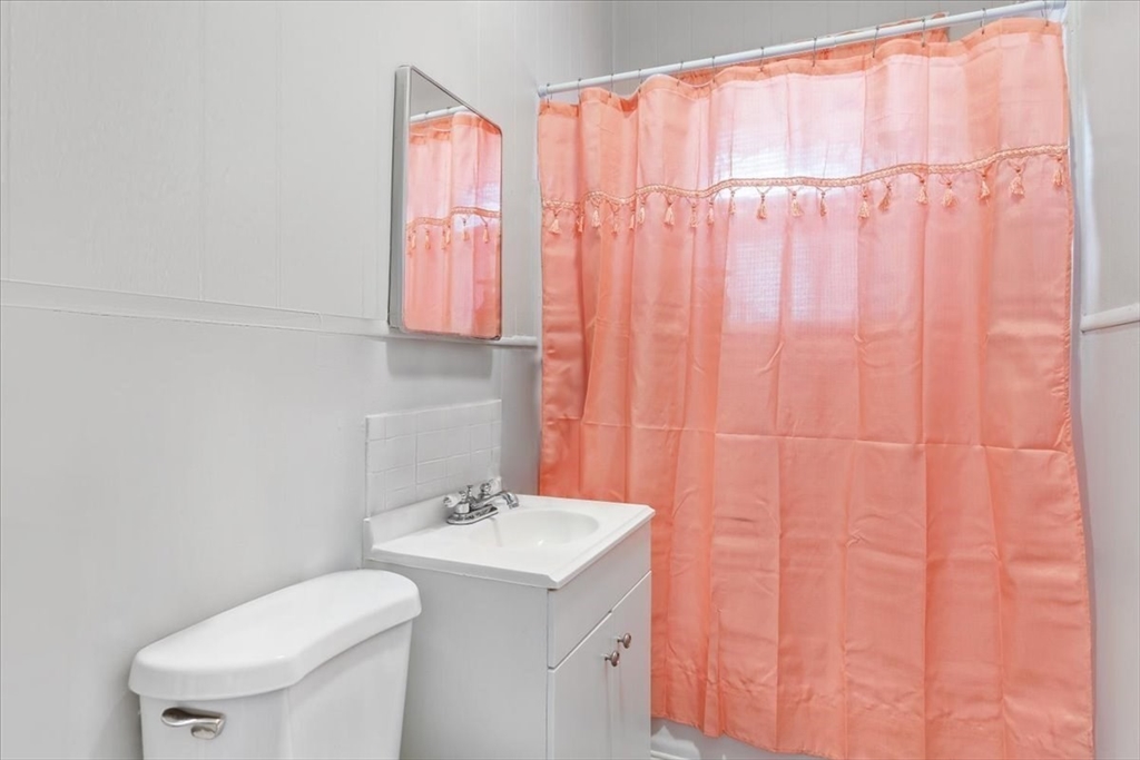 225 Mulberry Street Fall River, MA 02721 - Photo 3 of 13 a bathroom with a sink a toilet and a shower curtain