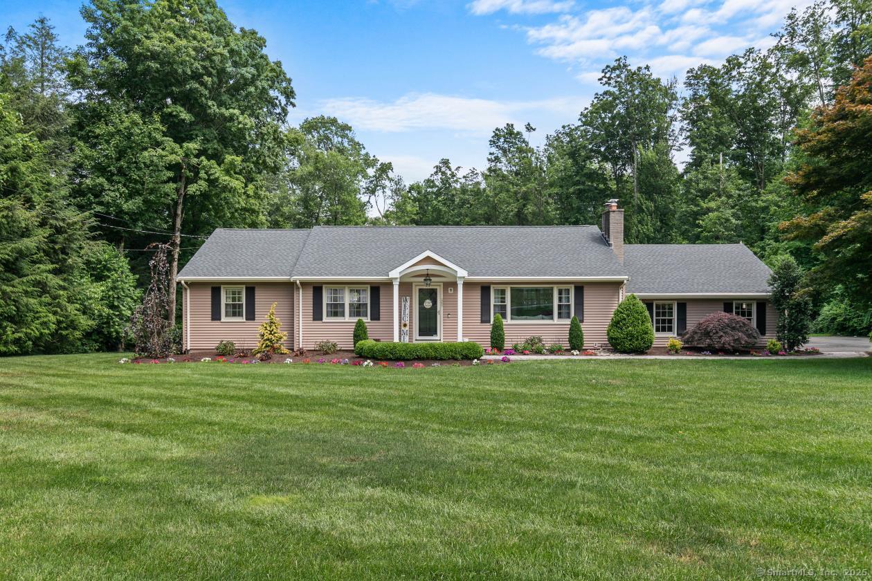 a front view of a house with garden and trees