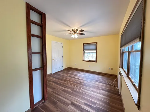 an empty room with wooden floor and a ceiling fan