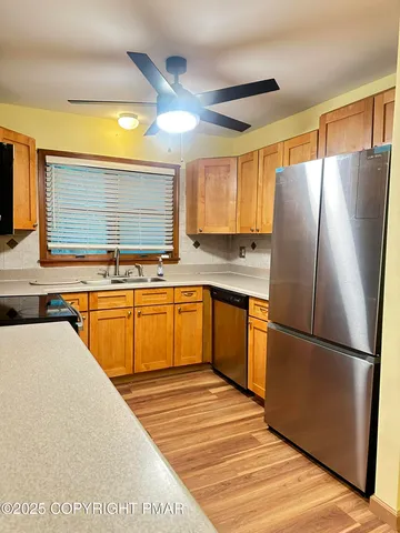 a kitchen with stainless steel appliances granite countertop a refrigerator a sink dishwasher a stove with wooden floor and cabinets