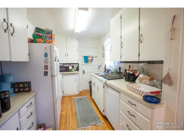 a kitchen with a refrigerator a stove and wooden floor