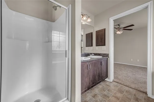 a bathroom with a granite countertop sink a mirror and a shower