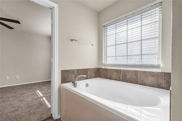 a white bath tub sitting in a bathroom next to a window