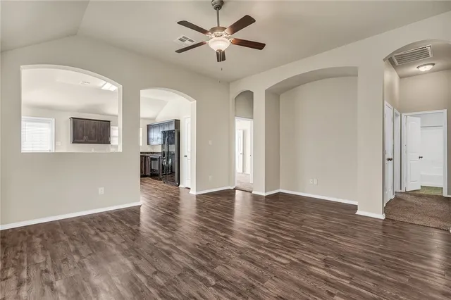 a view of an empty room with window and wooden floor