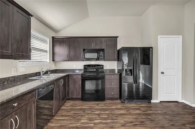 a kitchen with granite countertop a refrigerator stove and sink