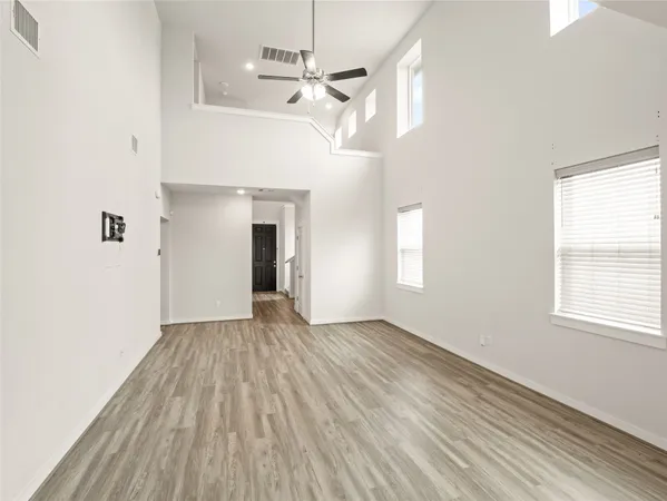 a view of empty room with wooden floor and fan