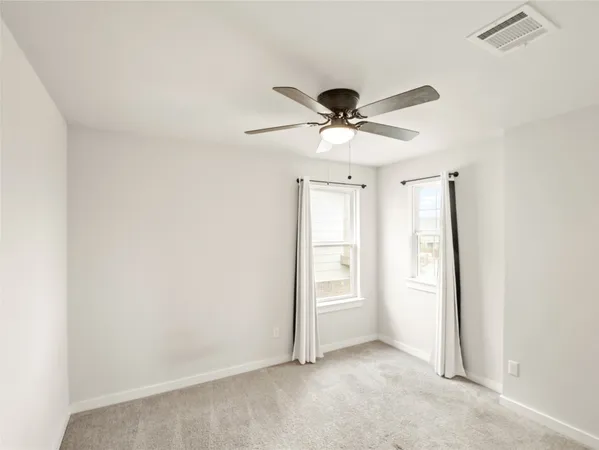 an empty room with a window and a ceiling fan