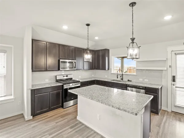 a kitchen with stainless steel appliances granite countertop a sink a stove a refrigerator and a oven with wooden floor