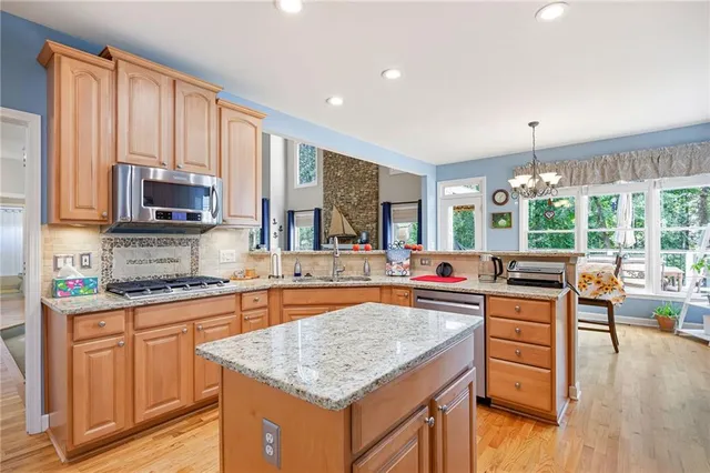 a kitchen with kitchen island granite countertop wooden cabinets a stove and a wooden floor