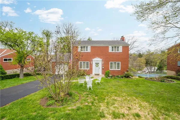 a brick house with a big yard plants and big trees