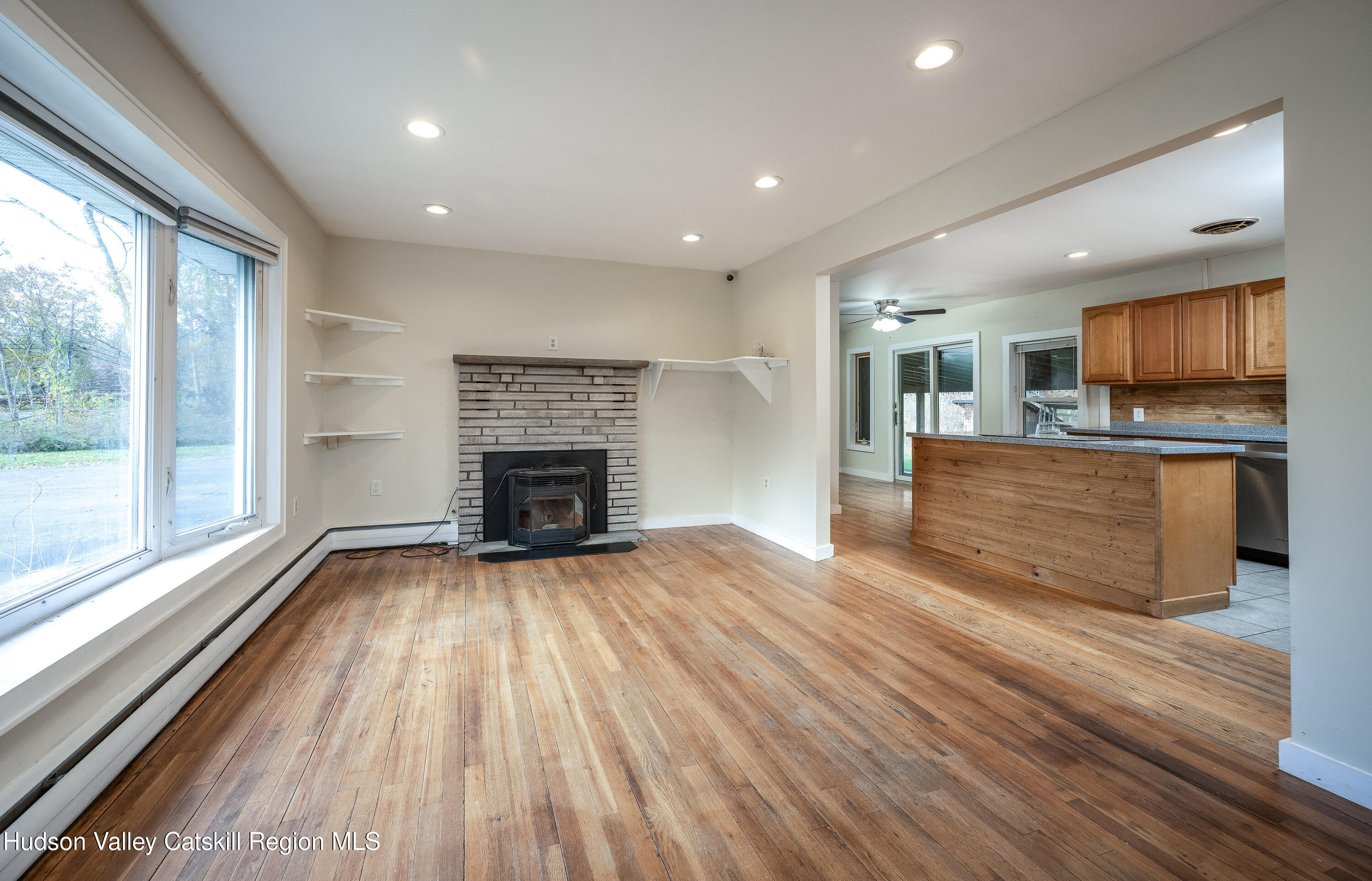 3024 Highway 213 Stone Ridge, NY 12484 - Photo 7 of 31 an empty room with wooden floor fireplace and windows