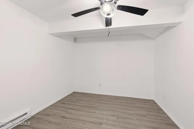 an empty room with a ceiling fan and wooden floor