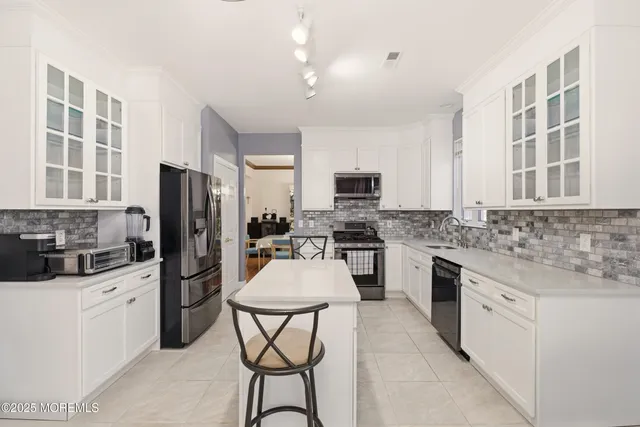 a kitchen with a refrigerator a stove a sink cabinets and a dining table